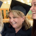 Three Grads in caps and gowns hugging