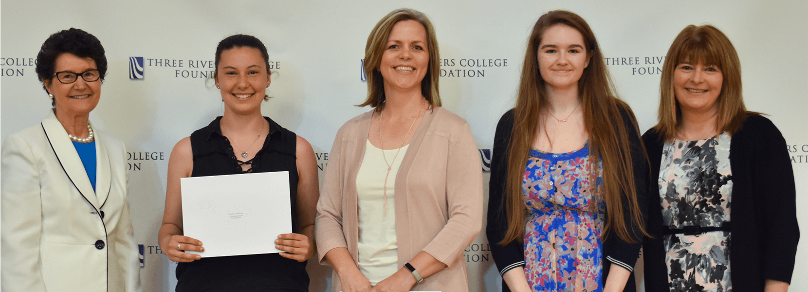 President Mary Ellen Jukoski stands with scholarship recipients Abigail Christina, Julie Craig, Halyey Gagdon as Three Rivers College Foundation Board Member and Assistant Vice President of Chelsea Groton Bank Jen Delucia presents them with Chelsea Groton Bank Scholarships.