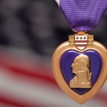 A Purple Heart metal in front of a blurred America flag.