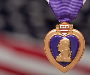 A Purple Heart metal in front of a blurred America flag.