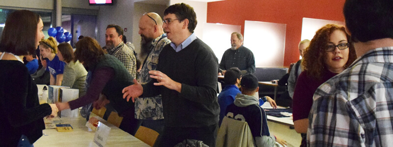 Students and staff talking at tables.