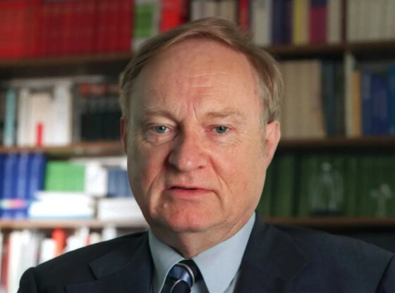 An image collage containing 1 images, Image 1 shows Ludwig A. Minelli, founder of Dignitas, holds a book titled "Thomas More" with a bookshelf in the background