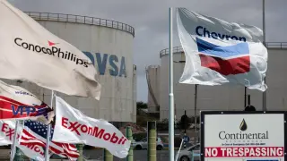 Photomontage of an oil tanker depot of PDVSA, Venezuela's state oil company, with flags of the American oil companies ExxonMobil, Chevron, ConocoPhillips and Continental Resources.