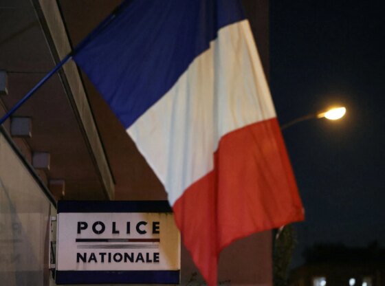 An image collage containing 1 images, Image 1 shows A French flag hangs above a "Police Nationale" sign at a police station at night